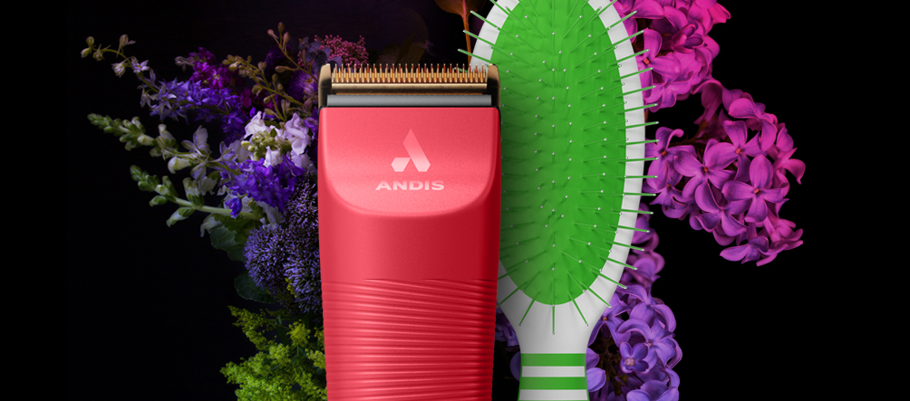 The Andis Vida Clipper and Pin Brush in front of spring flowers.