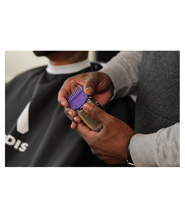 close up of man holding master cordless clipper attaching purple comb attachment