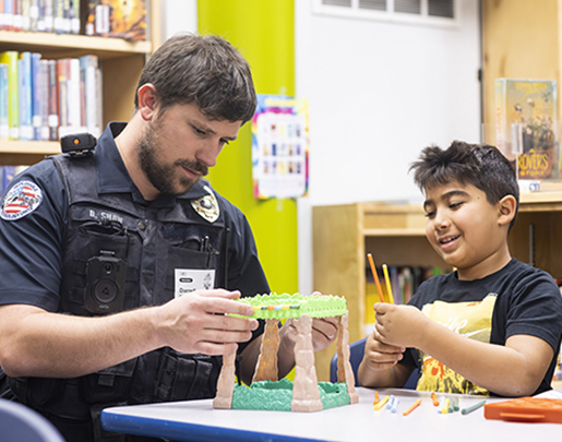 Police officer helping a student build a project